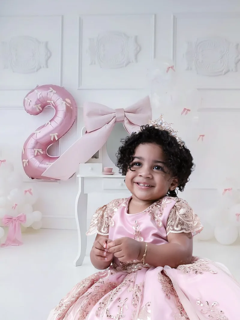 Smiling toddler in a pink gown and jewelled crown