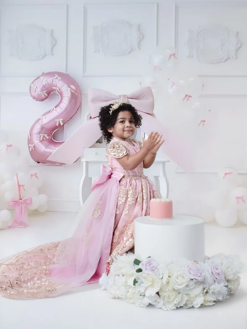 Toddler clapping in a pink gown at her birthday session