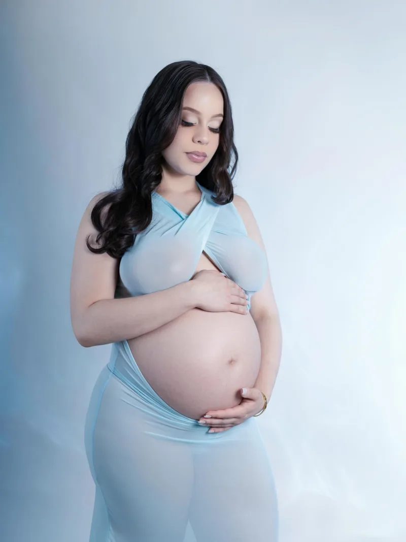 Maternity portrait in a pale blue gown on a soft blue background