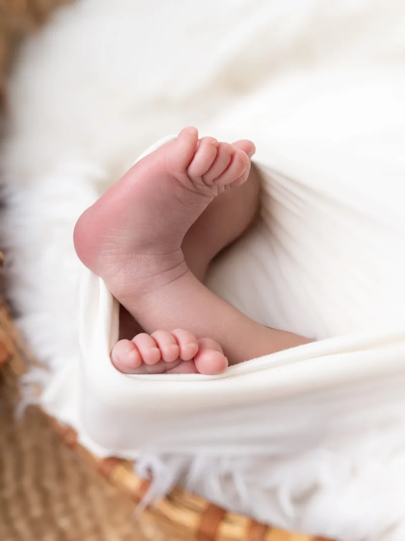 Close detail of a newborn's feet peeking from a wrap