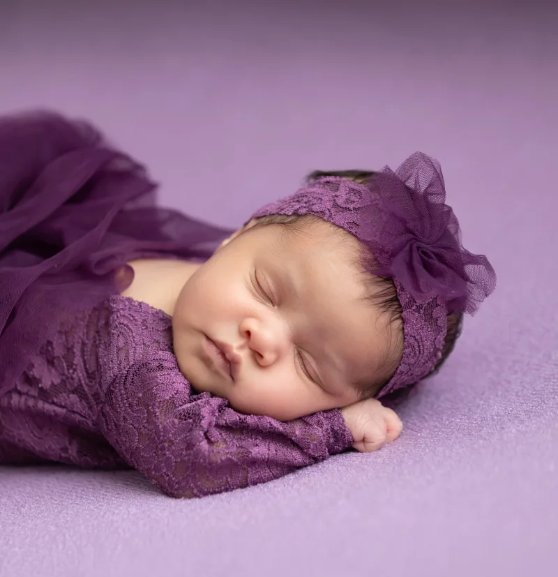 Newborn in plum lace with a matching flower headband