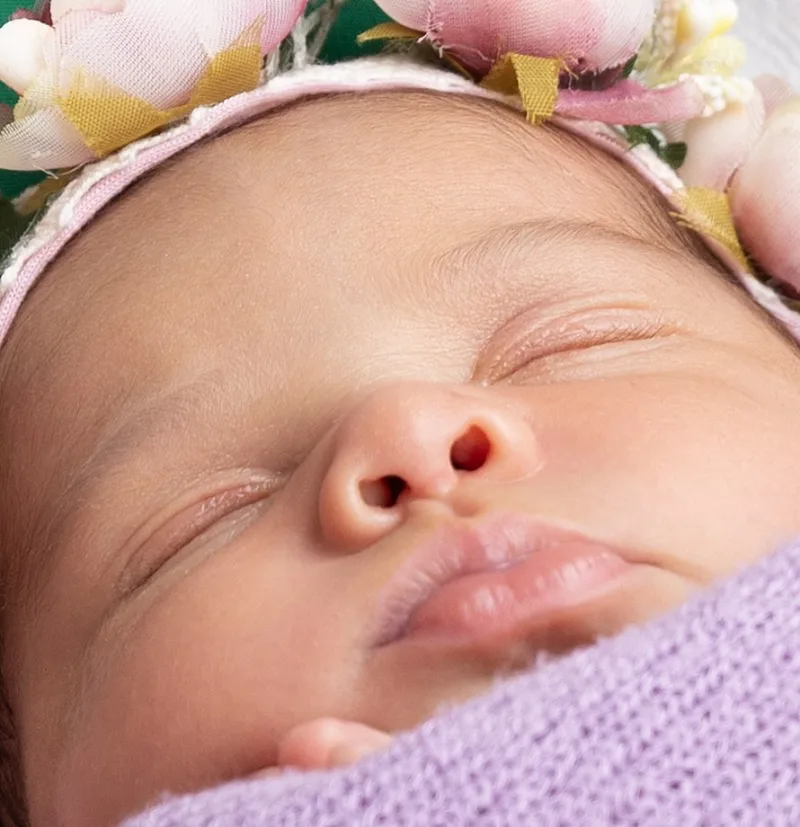 Close detail of a newborn wearing a pastel floral crown