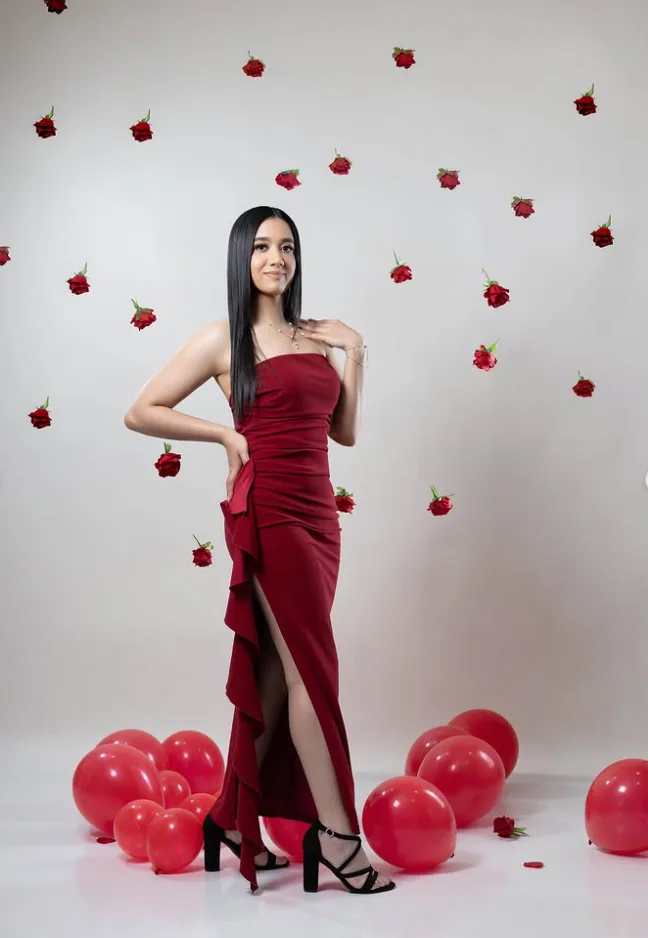 Portrait in a red gown surrounded by suspended roses and balloons